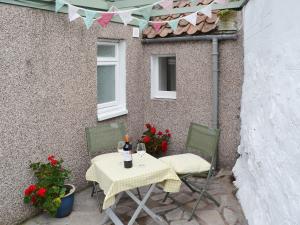 a table and chairs on a patio with flags and flowers at Well Cottage in Ceres