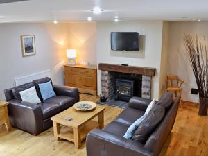 a living room with two leather couches and a fireplace at Aden Barn in Allonby