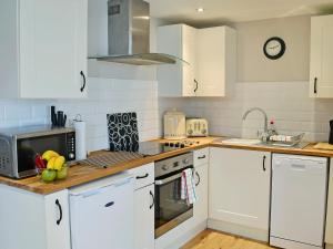 a kitchen with white cabinets and a stove top oven at Aden Barn in Allonby