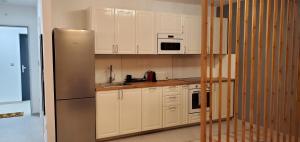 a kitchen with white cabinets and a stainless steel refrigerator at DN Rose Apartmant in Budapest