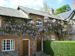 a brick house with a bunch of purple flowers on it at Cider Cottage - E5576 in Warkleigh