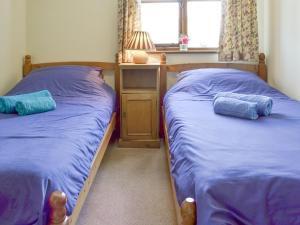 dwa łóżka w sypialni z niebieską pościelą w obiekcie Stable Cottage w mieście Ticehurst