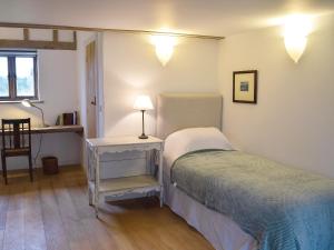 um quarto com uma cama e uma mesa com um candeeiro em Low Farm Barn em Laxfield