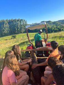 un grupo de personas sentadas frente a un carrito de golf en Casa de Campo Província Minosso, en Farroupilha