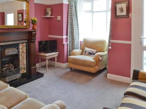 a living room with a fireplace and a chair and a television at Sea Folly in Brightlingsea