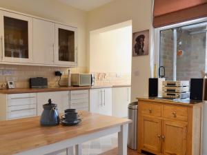 a kitchen with white cabinets and a wooden table at Cottage On The Green in York