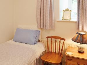 sypialnia z łóżkiem z niebieską poduszką i krzesłem w obiekcie Hammer Bank Lodge w mieście Windermere