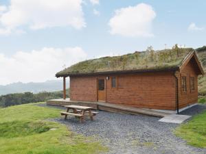 Cabaña de madera con banco y techo de hierba en Seascape, en Flodigarry