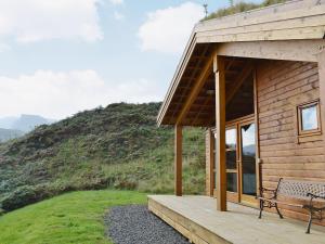 a wooden cabin with a bench on the porch at Seascape in Staffin