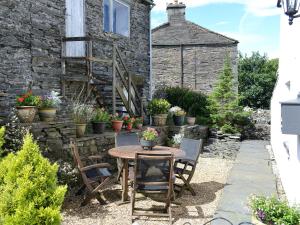 a patio with a table and chairs in front of a building at Riverside Cottage in Horton in Ribblesdale