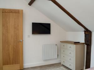 a bedroom with a tv on the wall and a dresser at Derbys Loft in Beccles