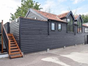 a black house with a wooden staircase in front of it at Derbys Loft in Beccles