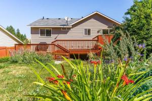 a house with a deck and a yard with flowers at Spacious home, gameroom, 9mi GEG, 5mi downtown, 5mi to hospitals, close to all universities in Spokane Valley