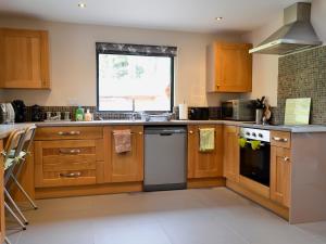 a large kitchen with wooden cabinets and a window at Glan-y-gors in Beddgelert