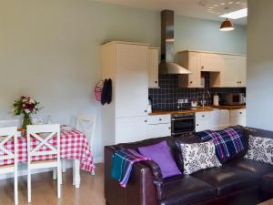 een woonkamer met een bank en een tafel en een keuken bij The Stables in Martin