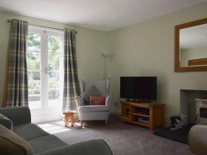 a living room with a tv and a couch and a chair at Toadhall in Aberfeldy