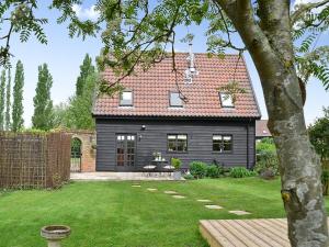 a black house with a red roof and a yard at The Old Stables in Rickinghall