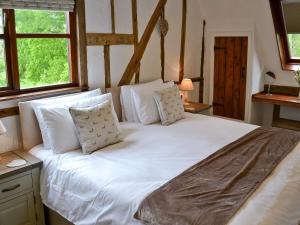 uma grande cama branca num quarto com janelas em The Old Stables em Rickinghall