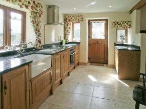 a large kitchen with wooden cabinets and a sink at Two Bridge Cottage in Winsham
