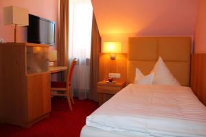 a hotel room with a bed and a desk and a television at Hotel-Gasthof-Kohlmeier in Kranzberg