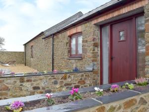 サンダースフットにあるSouthlands Barnの赤い扉と花の石造りの家