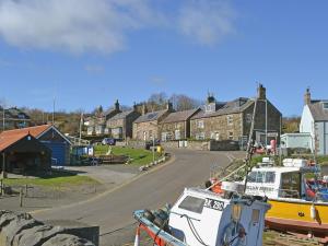a boat is docked next to a street with houses at Craster View in Craster