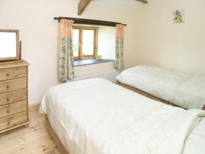 a bedroom with two beds and a window at Peartree Cottage in St Mellion