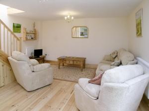 a living room with two couches and a table at Peartree Cottage in St Mellion