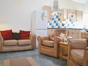 a kitchen with two couches and a white refrigerator at Yr Hen Ysgubor - 29176 in Trelech