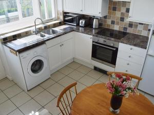 a kitchen with a washing machine and a table at Moles Leap in Brading