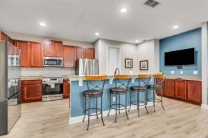 a kitchen with wooden cabinets and a blue island with bar stools at Huge 10 BDR Family House with Arcades and Free Pool Heat Near Disney in Orlando