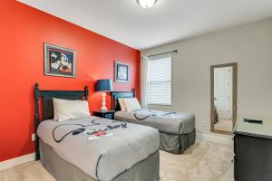 2 camas en una habitación con pared de color naranja en Huge 10 BDR Family House with Arcades and Free Pool Heat Near Disney, en Orlando