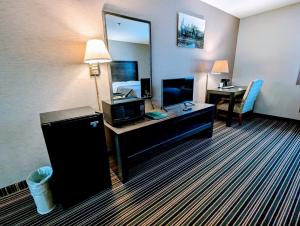 a hotel room with a bed and a desk with a television at Woodfield Inn and Suites in Marshfield