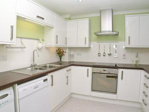 a kitchen with white cabinets and a sink at Kerrera View in Oban