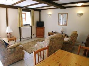 a living room with chairs and a table and a tv at Jemima Cottage in Saint Martins Green