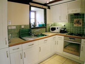 a kitchen with white cabinets and a sink at Jemima Cottage in Saint Martins Green