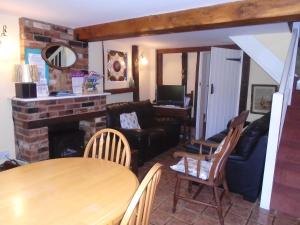 a living room with a table and a fireplace at Whipple Tree Cottage in Cratfield