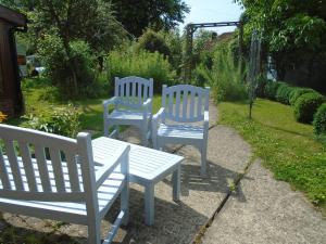 three blue and white benches sitting in a garden at Whipple Tree Cottage in Cratfield