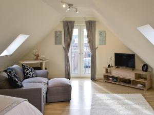 a living room with a couch and a tv at The Studio in Warkworth