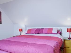 a bed with pink and white sheets and two lamps at Lochview in Milovaig