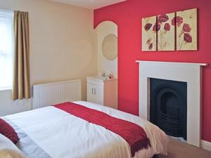 ウィットビーにあるCobweb Cottageの赤いベッドルーム(ベッド1台、暖炉付)