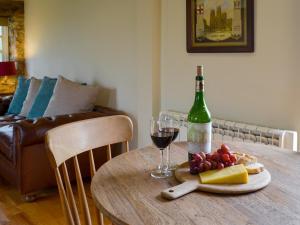 a table with a bottle of wine and wine glasses at Bell Cottage in Gristhorpe