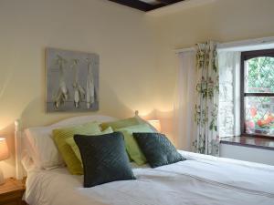 a white bed with green pillows in a bedroom at Bwthyn in New Quay