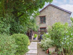 una antigua casa de piedra con una puerta y un jardín en Bwthyn en New Quay