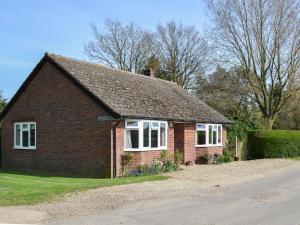 a red brick house with white windows on a street at Poplar Bungalow in Lyng