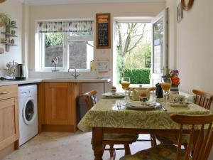 Poplar Bungalow في Lyng: مطبخ مع طاولة وكراسي ومطبخ مع غسالة صحون