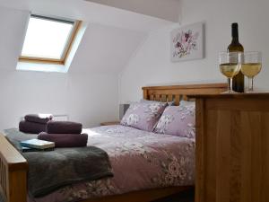 a bedroom with a bed and two glasses of wine at Willow Cottage in Woolfardisworthy