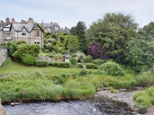 a house with a river in front of it at The Garden Rooms in Corbridge