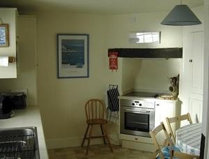 uma cozinha com um fogão e uma cadeira em 3 The Coastguards em Downderry