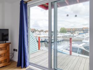 a sliding glass door with a view of a marina at Jib Sail-18148 in Wroxham
